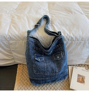 Close-up of vintage washed denim tote bag featuring two front pockets and adjustable strap
