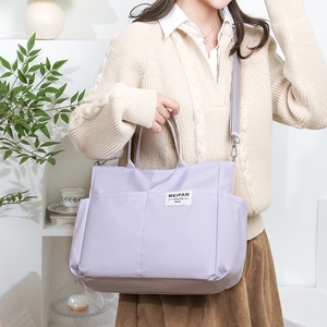 Close-up of a purple nylon tote bag with side pockets and adjustable strap on a model