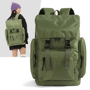 Detail view of large green checkered backpack with buckle straps and multiple pockets
