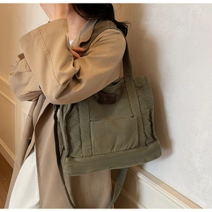 Detail of army green canvas tote bag with brown leather patch and dual handles