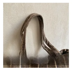 Detailed close-up of brown striped canvas tote bag showing reinforced sewing and fabric texture