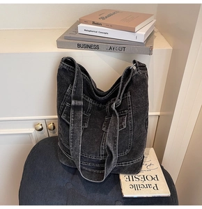 Detail view of washed black denim tote bag with contrast white stitching and front pockets