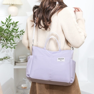 Detail of light purple nylon tote bag showing side pocket and adjustable white shoulder strap
