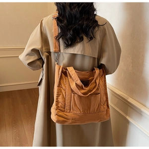 Brown canvas tote bag detail showing adjustable shoulder strap and leather brand tag