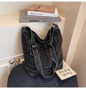 Close-up of washed denim tote bag with front pocket on a blue velvet stool