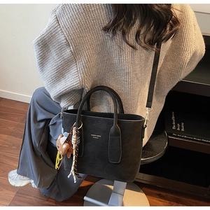 Détail du sac seau noir avec pendentif ours et bandoulière réglable pour femme