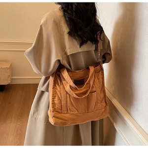 Detail of caramel canvas tote bag with adjustable shoulder strap and brown leather patch