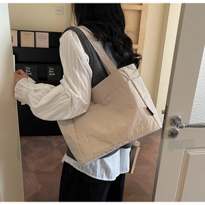 Makroaufnahme der beigen Nylon-Tragetasche mit Seitentaschen und gewebtem Markenetikett