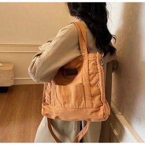 Canvas tote bag in mustard yellow with dual handles and shoulder strap shown on model