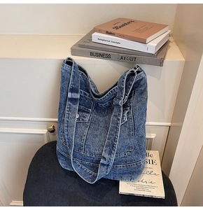 Detail of adjustable strap and washed denim texture of a vintage blue tote bag