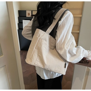 Detail einer hellbeigen Canvas-Tasche mit Seitentaschen und gewebtem Markenlabel