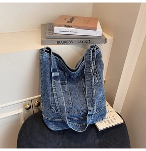 Detailed close-up of washed denim tote bag featuring multi-pocket workwear design