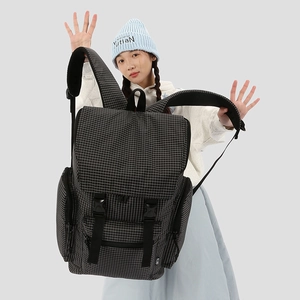 Close-up of black and white plaid backpack with buckle straps and multiple pockets