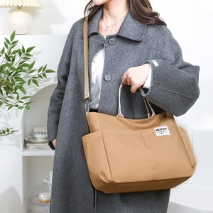 Close-up of khaki nylon multi-pocket tote bag showing side pockets and woven shoulder strap