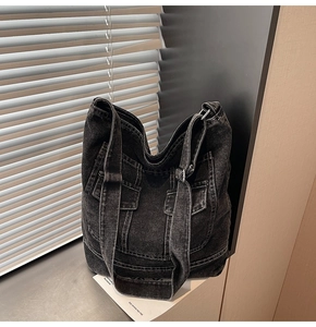 Detail of dark denim tote bag featuring contrast stitching and utilitarian cargo pockets