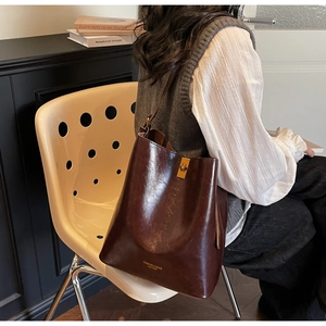 Detail of dark brown oil wax leather bucket bag with gold hardware in home setting