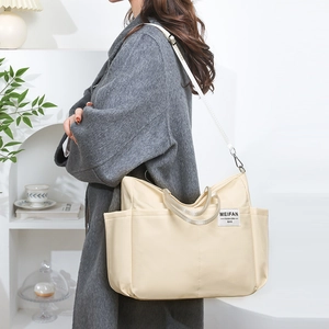Side view of beige nylon tote bag with multiple pockets and adjustable shoulder strap