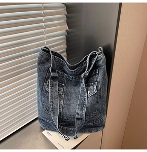 Detail of blue washed denim tote bag featuring two front cargo pockets with silver snaps