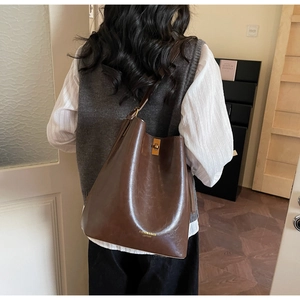 Detail of dark brown polished leather bucket bag with gold clasp and brand logo base