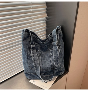 Detailed texture of washed denim tote bag with functional pockets and silver buckles