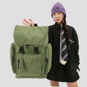 Detail of green checkered backpack showing side buckles, zip pockets, and large capacity