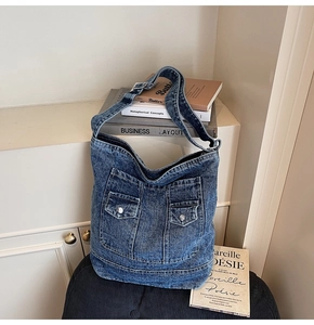Detail of vintage washed denim tote bag featuring dual front cargo pockets and metal buttons