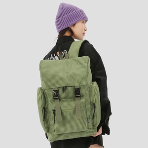 Detail view of green checkered backpack with buckle closure and multiple zipper pockets