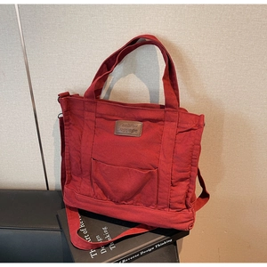 Detailed shot of dark red canvas tote bag with leather patch and reinforced handles