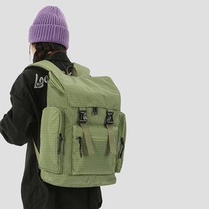 Close-up of green checkered backpack featuring multi-pocket design and sturdy black buckles