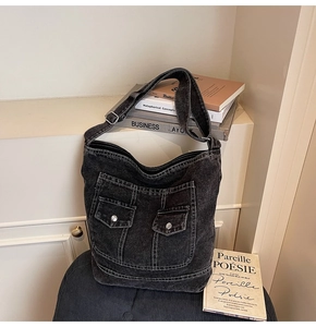 Detail of black washed denim tote bag with jeans pocket design and silver buttons