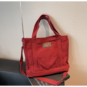 Detail of vintage dark red canvas tote featuring leather brand tag and front slip pocket