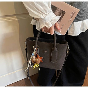 Detail of vintage brown suede bucket bag with gold logo and cute bear charm pendant