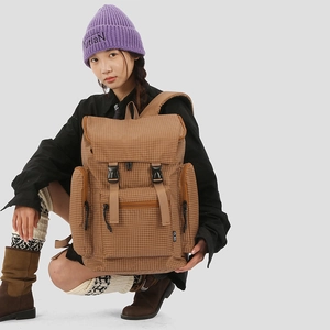 Detail shot of brown checkered backpack showing plastic buckles and functional front pockets
