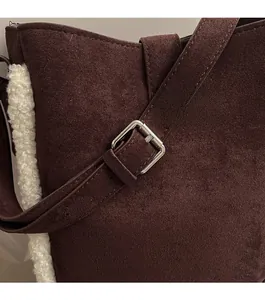 Detail der dunkelbraunen Wildleder-Tasche mit weißem Lammfell-Besatz und Silberschnalle