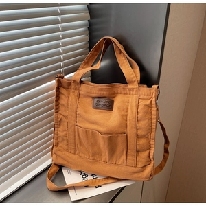 Detail of caramel canvas tote bag with leather patch, side pleats and adjustable strap
