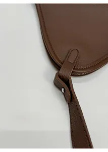 Vue détaillée de la boucle de sangle renforcée sur un sac en cuir grainé marron foncé