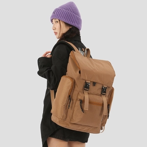 Detail view of large brown checkered backpack with multiple pockets on a female model