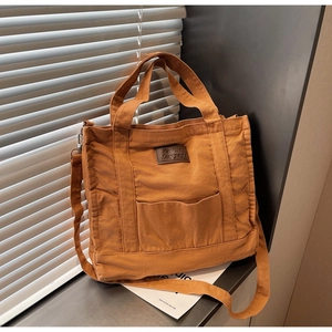 Close-up of canvas tote bag showing leather label detail and metal strap hardware