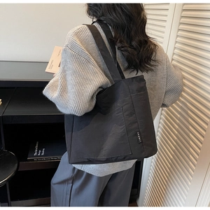 Detailaufnahme einer schwarzen Stoff-Tote-Bag mit minimalistischem Markenlabel und Außentasche