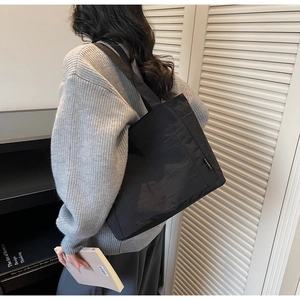 Detail einer wasserdichten schwarzen Nylon-Einkaufstasche mit weißem Webetikett und Trageriemen