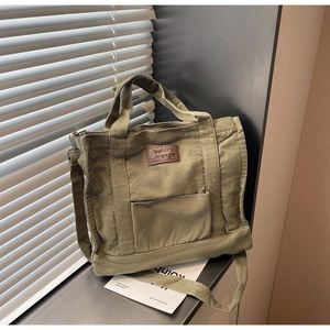 Detail of vintage canvas tote bag with leather logo tag and adjustable shoulder strap