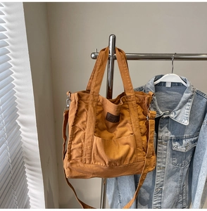 Detail of caramel canvas tote with adjustable strap and leather Fashion Leisure logo patch