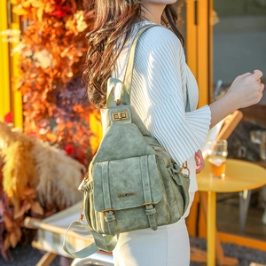Detail of green soft leather backpack with gold buckles and twist lock in outdoor setting