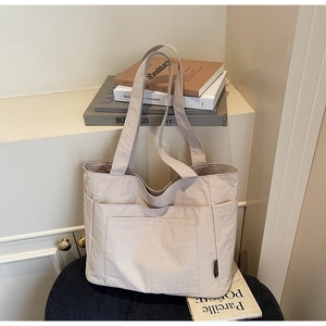 Detailansicht der beigen Mehrfachtaschen-Tragetasche auf Hocker im minimalistischen Stil