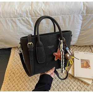 Détail du sac seau noir avec des breloques étoiles et des ferrures métalliques rétro