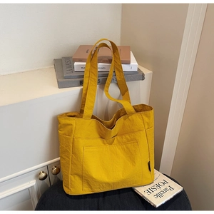 Makroaufnahme einer gelben Nylon-Tragetasche mit Vordertasche und seitlichem Webeetikett