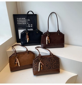 Détail de quatre sacs cabas en daim mat de diverses couleurs avec perles en bois