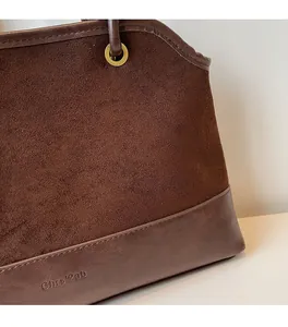 Détail du sac fourre-tout en daim vintage montrant les coutures et le logo embossé