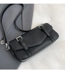 Detalle del bolso bandolera negro de piel con grano de lichi y hebillas de metal plateado