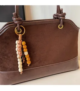 Vue détaillée du sac cabas en daim marron avec gland en perles de bois et anneau métallique